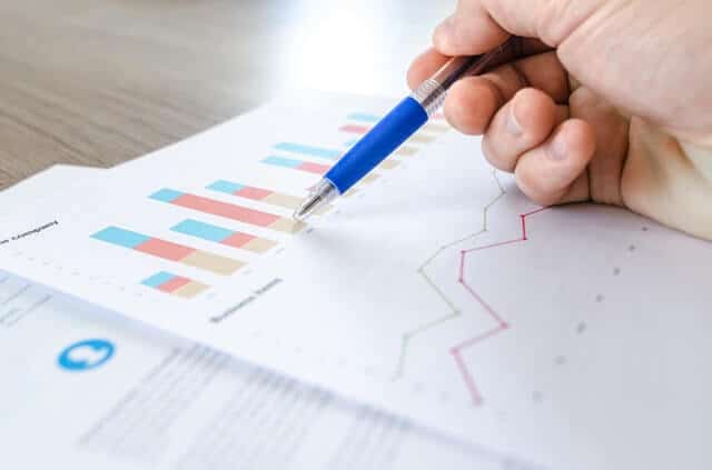 Person holding pen over sheets of research data.