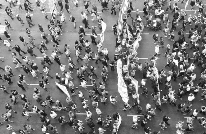 black and white Arial image of protesters walking a street carrying banners