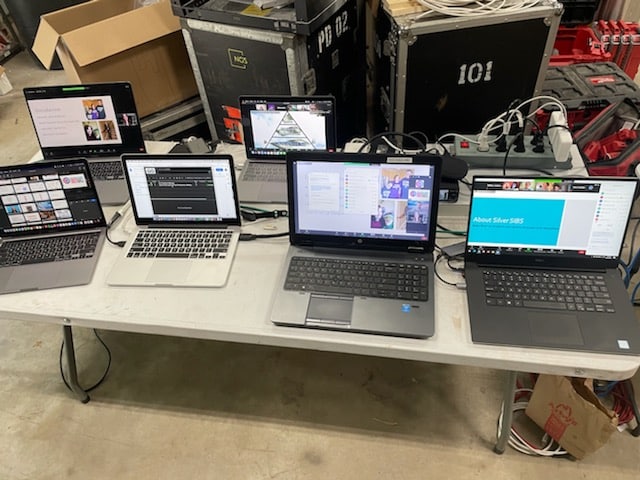 top shot of 5 laptops on a table playing different videos